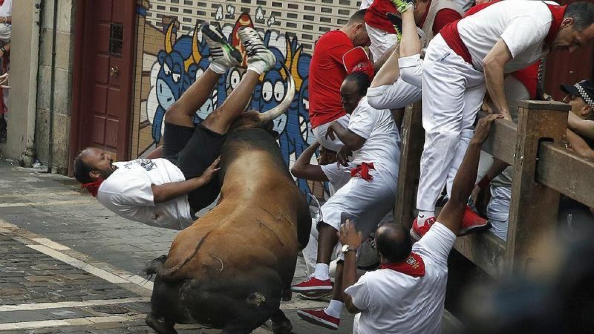Un toro de la ganadería de Cebada Gago embiste a un mozo a su paso por la curva de Mercaderes, durante el segundo encierro de los Sanfermines de 2016, uno de los más largos de los últimos años, con cinco minutos y cuarenta y cuatro segundos de duración.