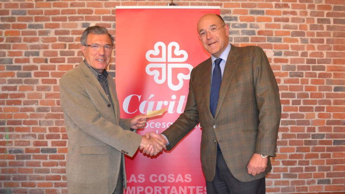 José Luis Lorenzana, administrador de Cáritas, recibe el cheque de manos de Ignacio Hurtado, abad de JHS
