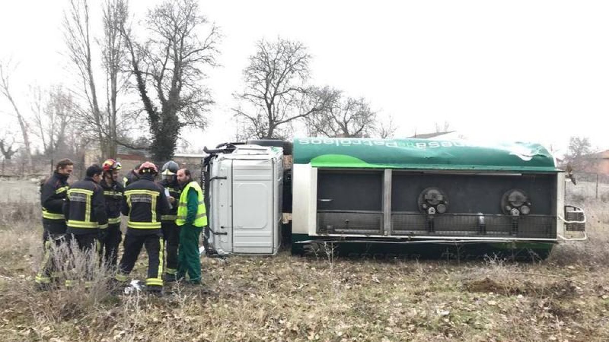 Los bomberos y el conductor del camión, junto al vehículo siniestrado.