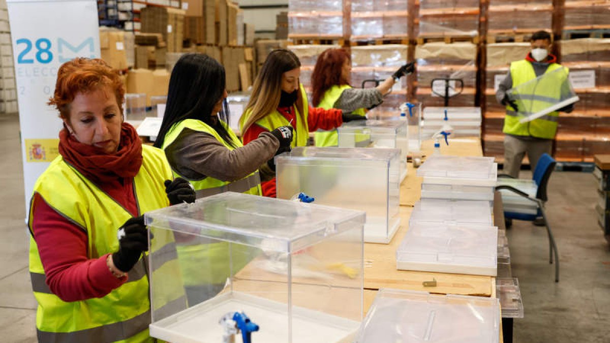 Varios operarios trabajan en las urnas en el centro logístico para las elecciones locales y autonómicas del 28-M, en Alcalá de Henares. CHEMA MOYA