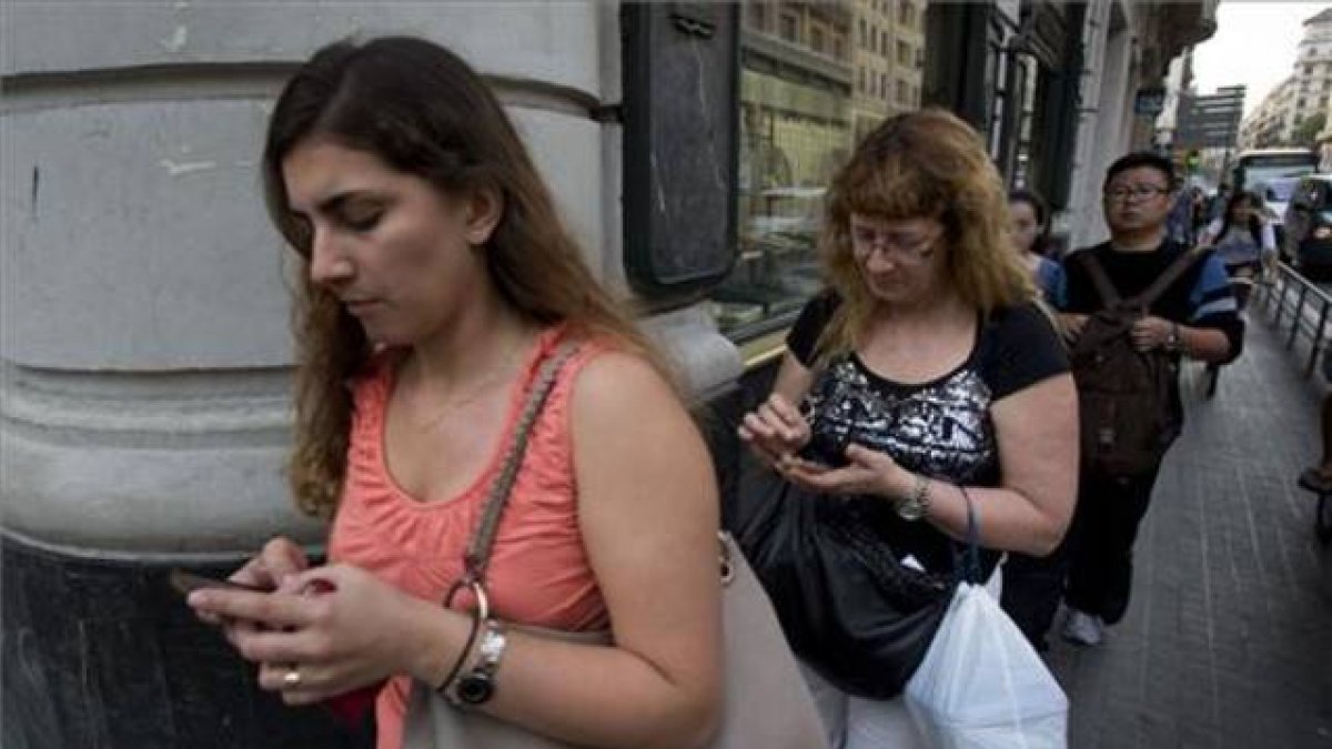 Usuarios de 'smartphones' chateando mientras caminan.