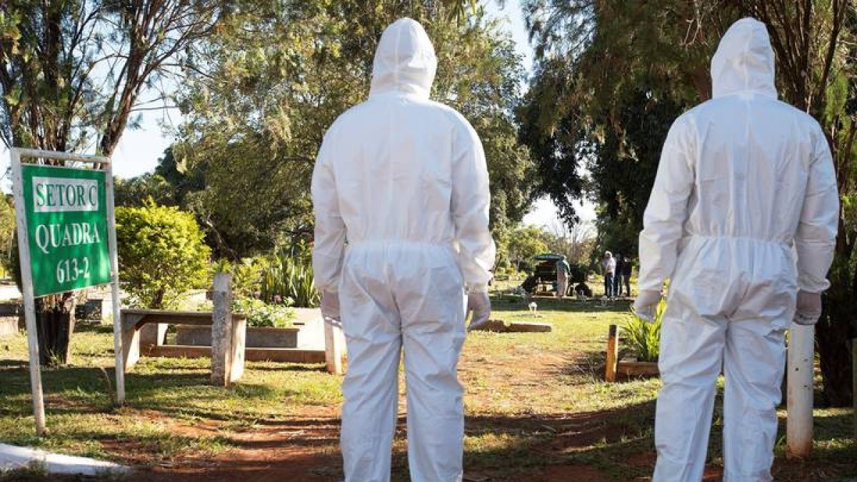 trabajadores de servicios funerarios observan luego de dejar a una víctima de covid-19. JOÉDSON ALVES