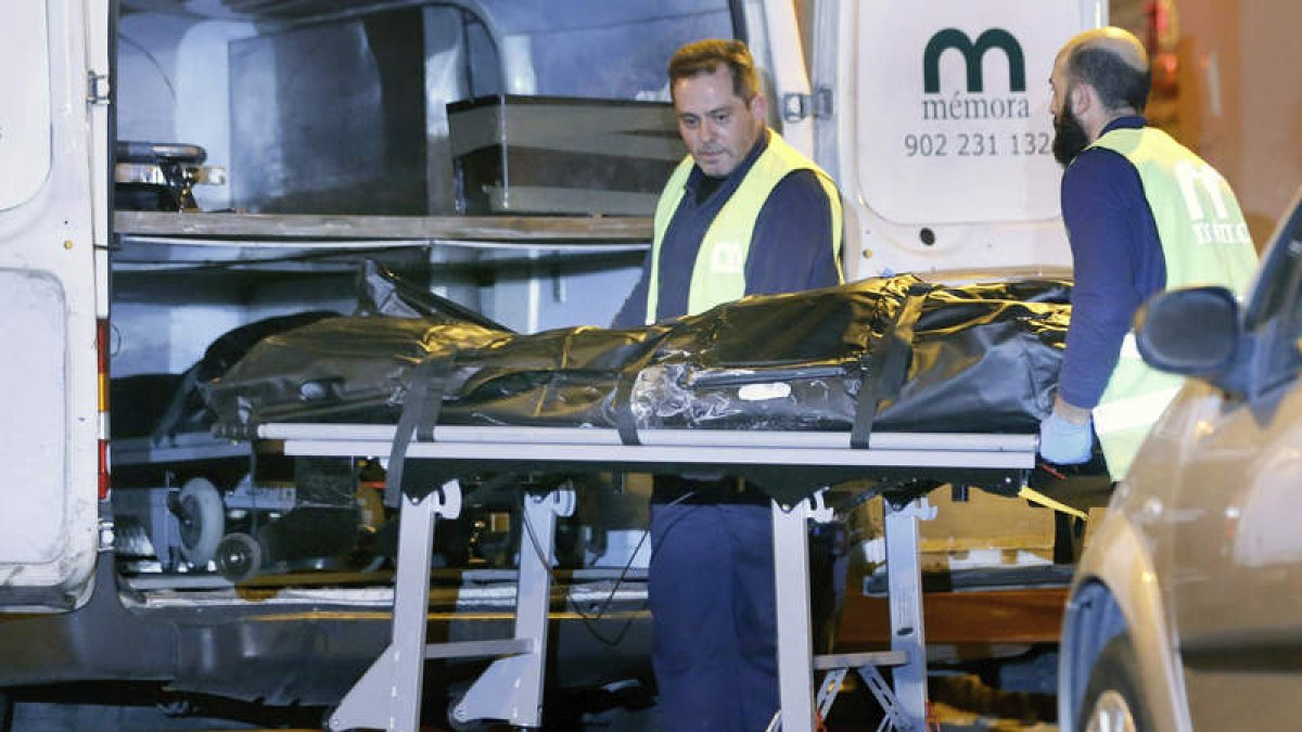 Funcionarios del retén fúnebre trasladan a la fallecida.