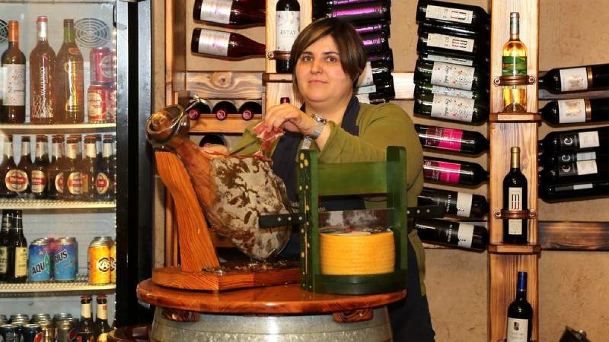 Irene Arias cortando jamón, que pone de tapa, en su establecimiento La Despensa de Puerta Moneda, en la esquina entre la calle Escurial y Puerta Moneda, en el barrio del Mercado.