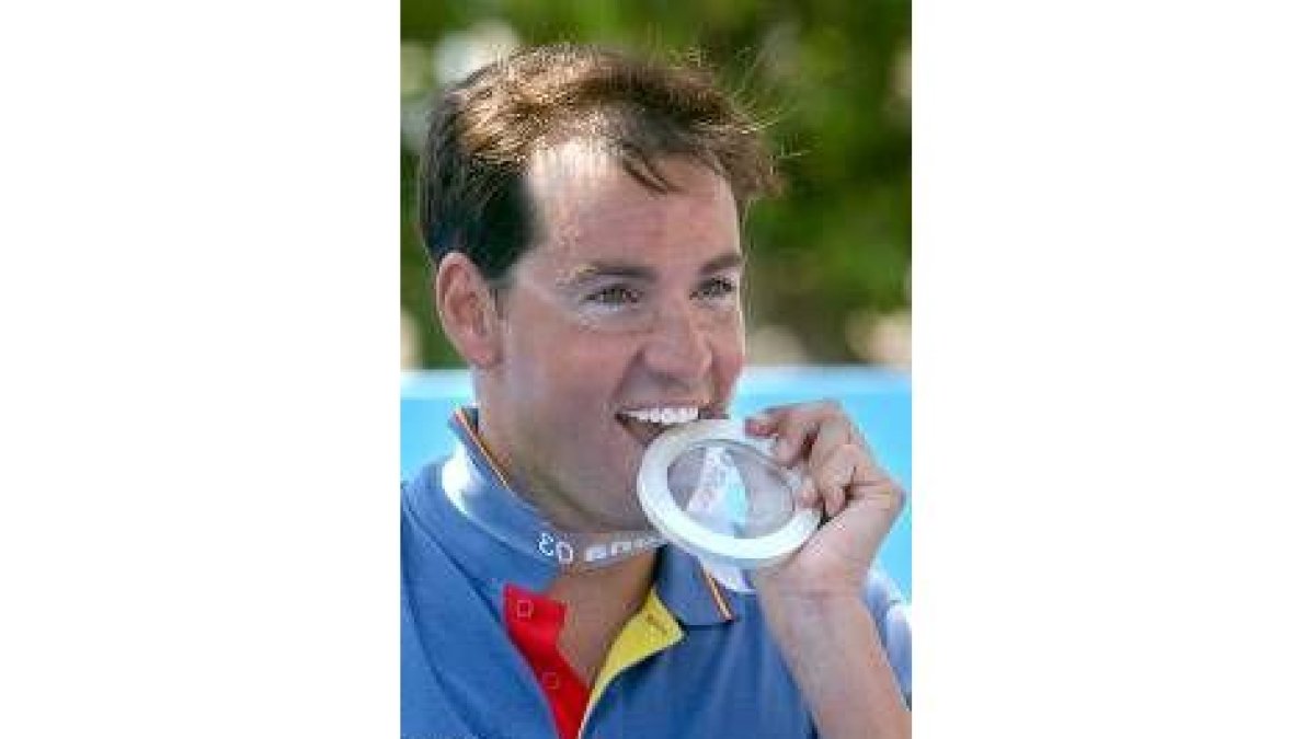 David Meca se muestra sonriente mordiendo la medalla conseguida