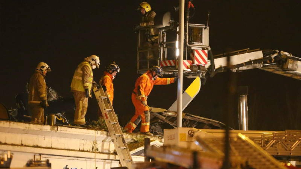Los bomberos trabajan en el pub en el que se estrelló el helicóptero de la policía.