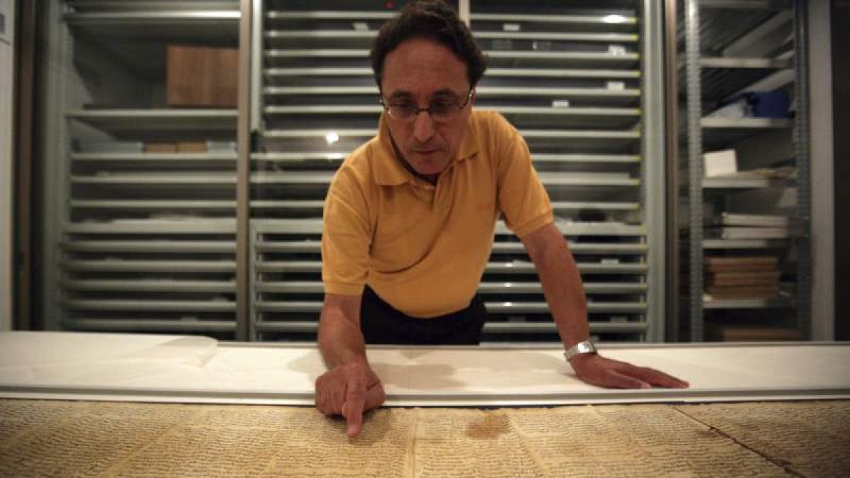 El comisario del Palacio del Libro, Adolfo Roitman, señala una parte del original de Isaías, uno de los rollos del Mar Muerto.