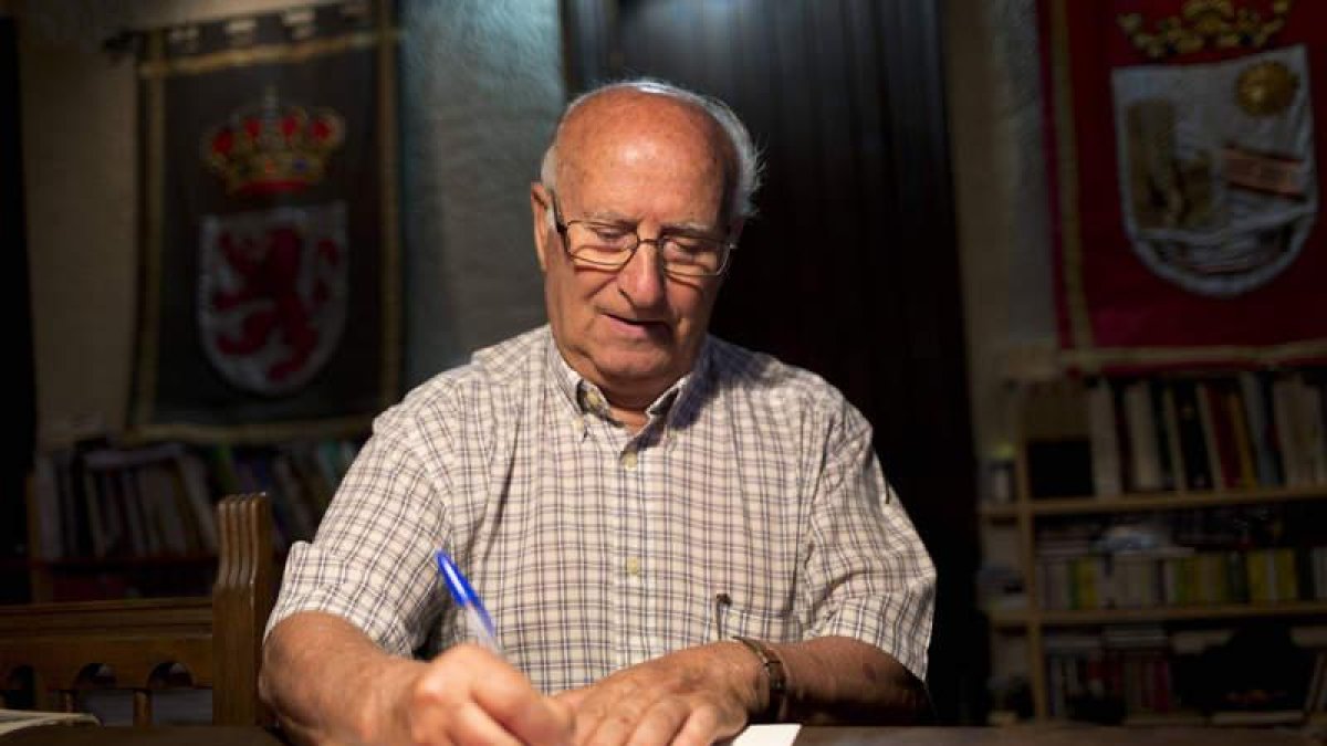 En el salón, dentro del torreón, este profesor jubilado escribe una dedicatoria en uno de sus libros.