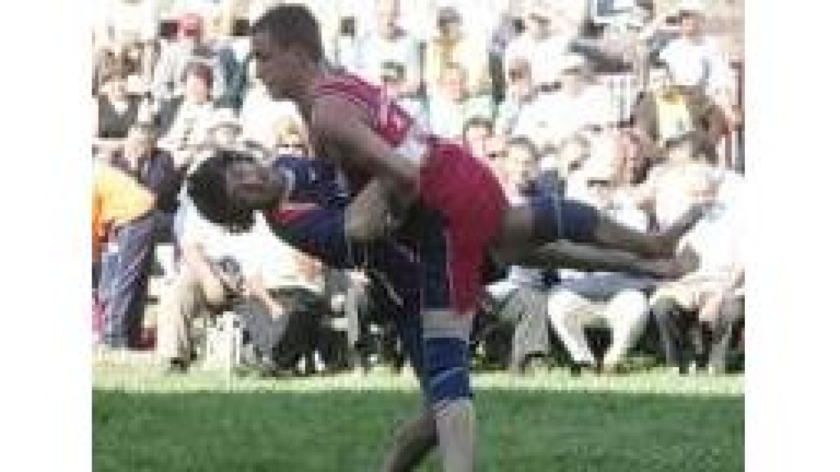 Uno de los luchadores levanta el trofeo que le acredita como triunfador