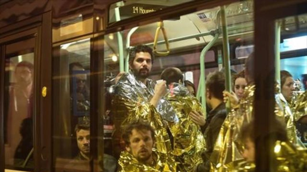 Evacuación 8 Varias personas abandonan la zona de El Bataclan en autobús y cubiertos con mantas de aluminio.