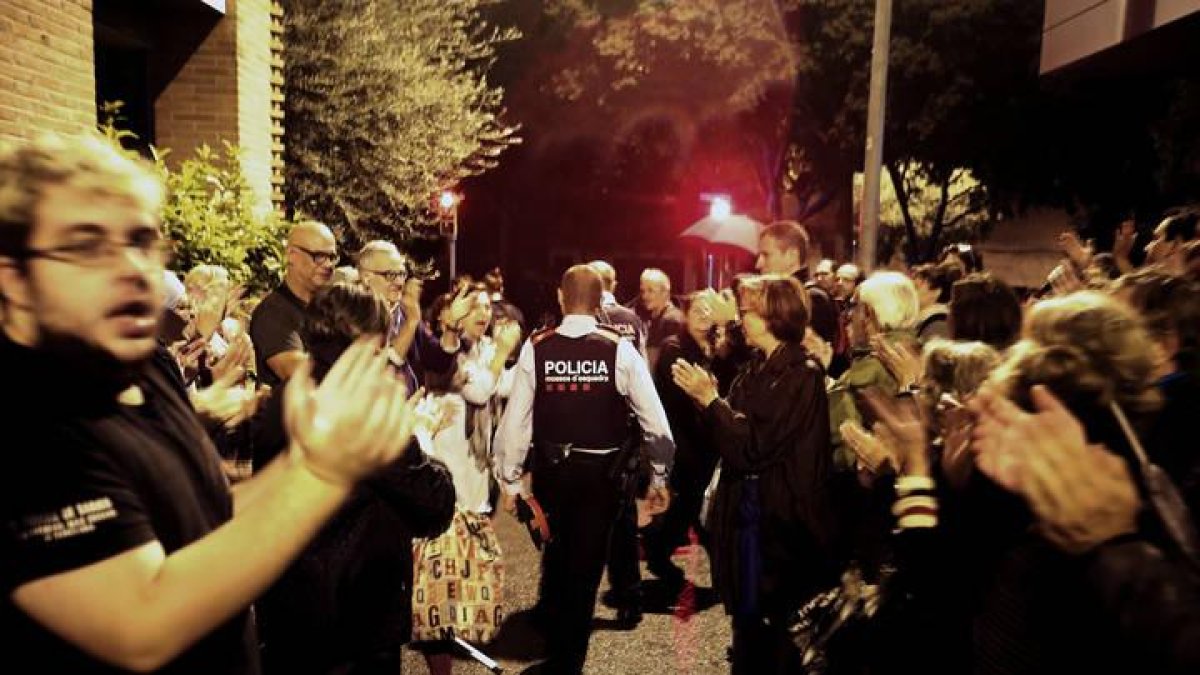 Una pareja de Mossos d'Esquadra salen entre aplausos de una escuela del barrio de Sarriá de Barcelona.