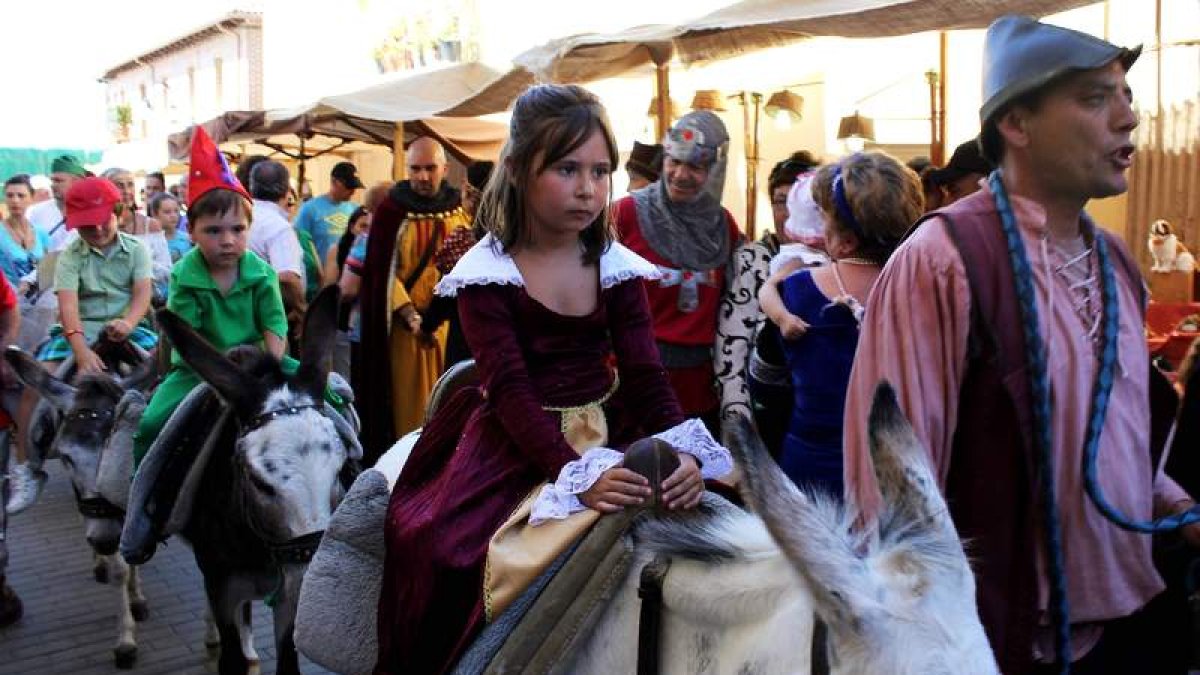 Niños y niñas disfrutan de un paseo en burro por el mercado medieval.