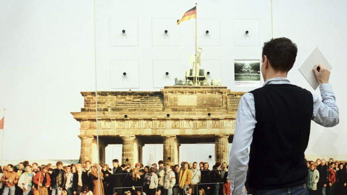 Un hombre ante una imagen interactiva de la caída del muro. Derecha, Una instalación que permanece sin las cruces blancas que fueron colocadas en memoria de las víctimas que perdieron la vida en el muro de Berlín