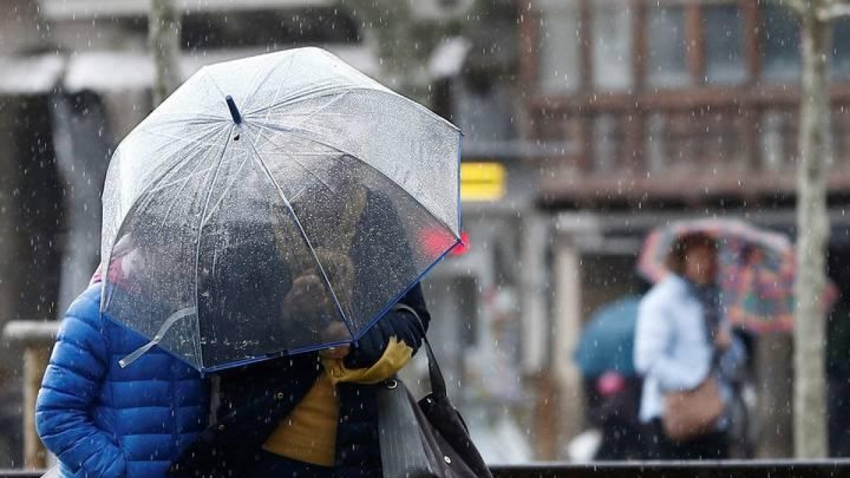Dos personas se protegen de la lluvia y el viento
