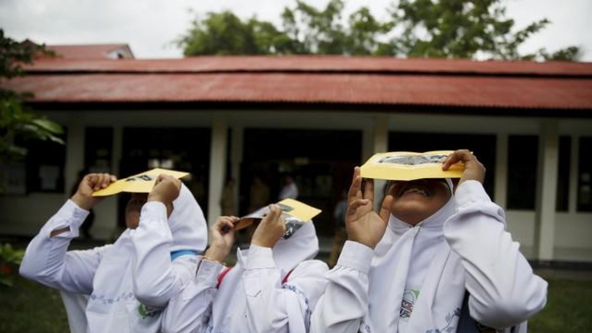 Un grupo de estudiantes prueban unos filtros para observar el eclipse de sol, este lunes en la isla indonesia de Ternate.