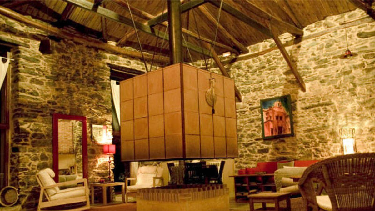 Salón de Casa Amagada, con su espectacular chimenea en el centro. Una de la estacncias comunes y un dormitorio.