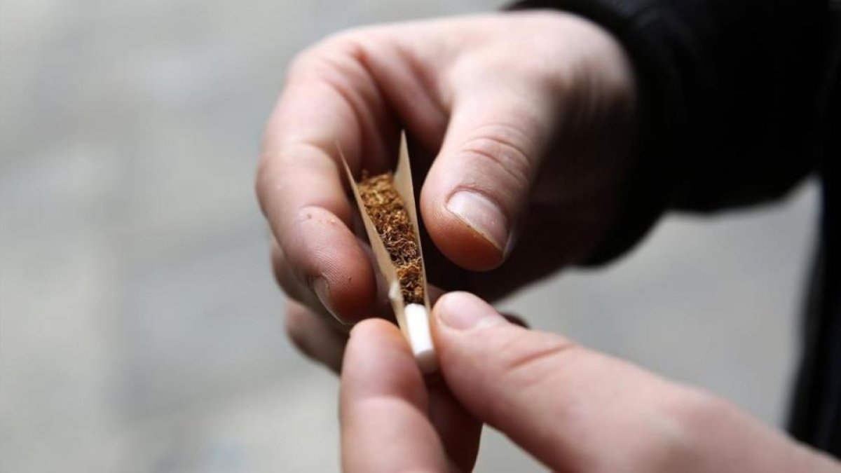 Un hombre lía un cigarrillo.