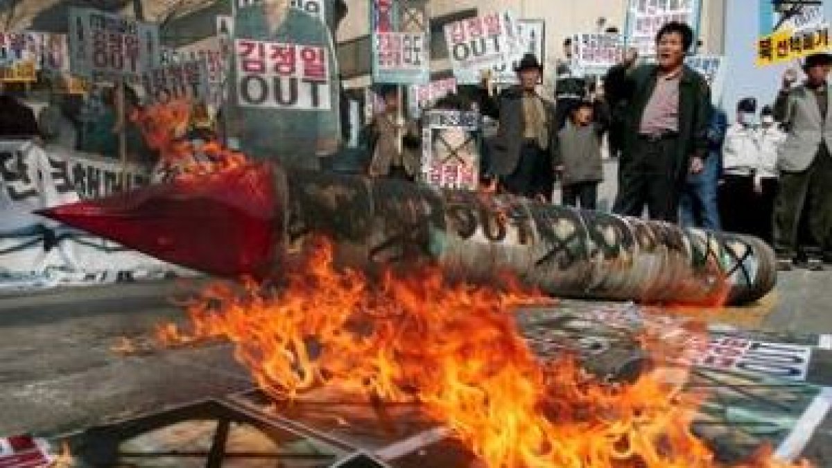 Un grupo de personas quema retratos del líder norcoreano, Kim Jong-Il