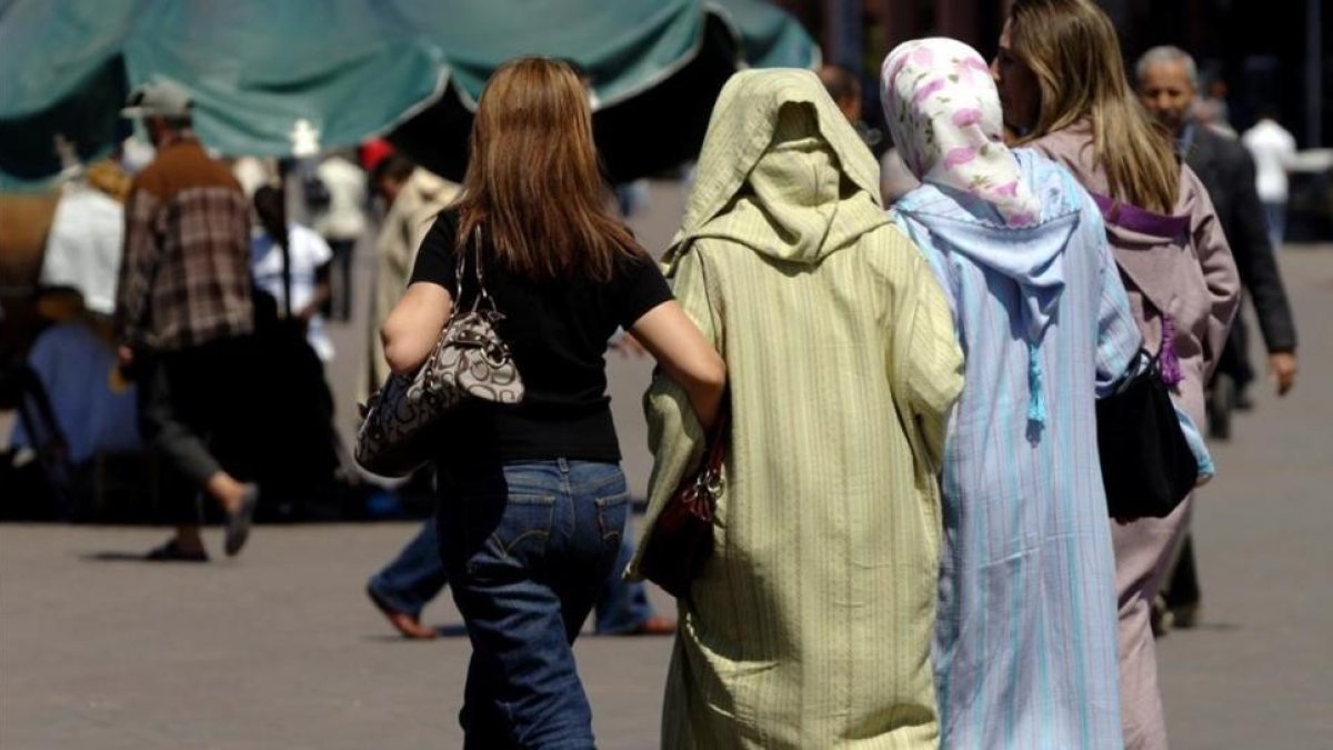 Mujeres vestidas al uso occidental junto a otras con vestimentas tradicionales, en la plaza Jemaa El Fna, en Marraquech, en una imagen de archivo.