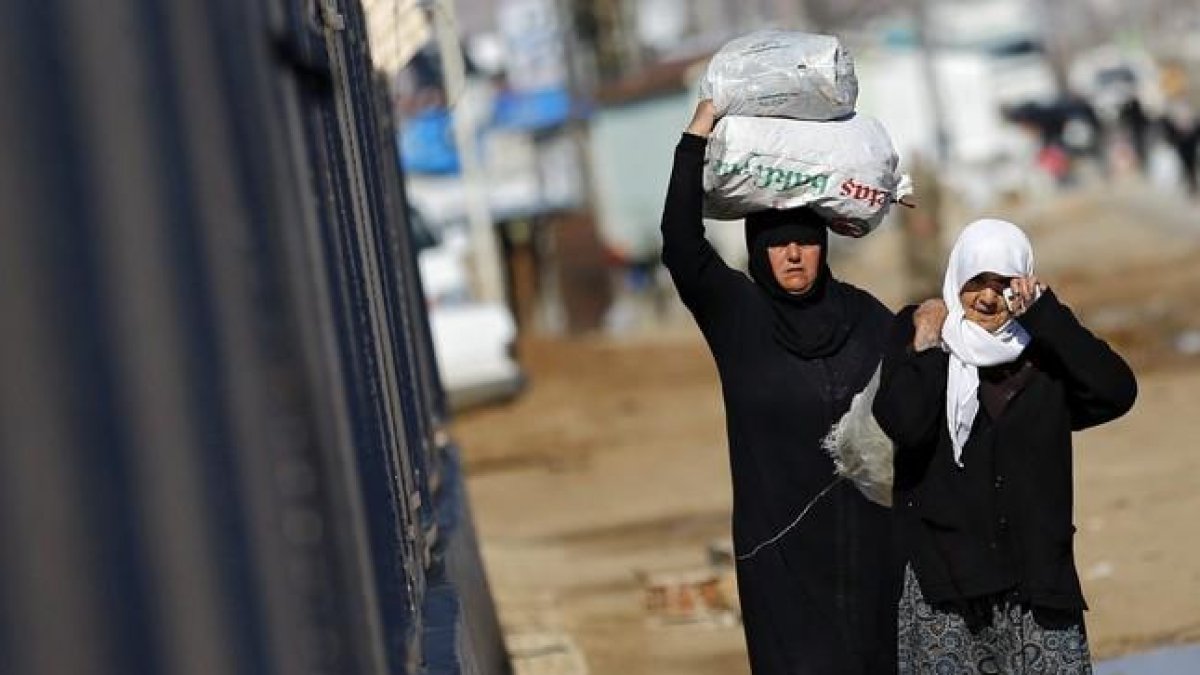 Refugiados sirios trasladan bolsas de alimentos en el paso fronterizo de Öncüpinar, en Kilis, Turquía.