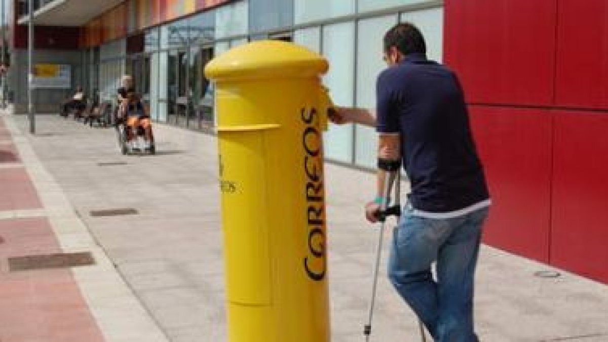 Una persona deposita una carta en el buzón ubicado al lado del centro de discapacitados.