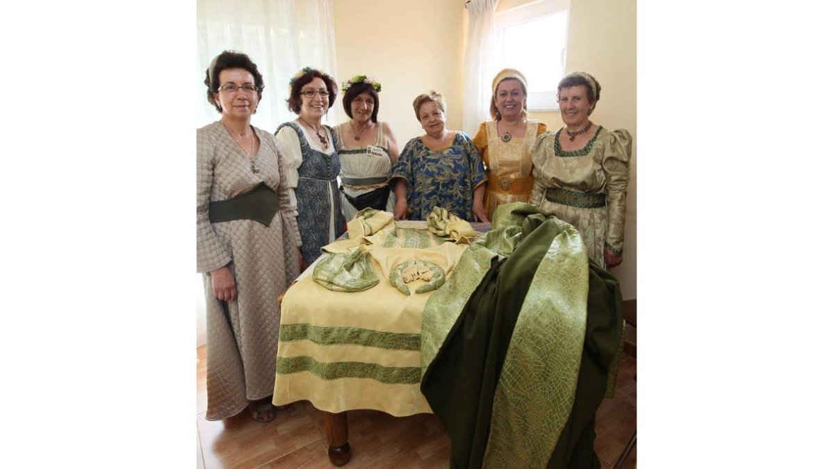 Las seis costureras posan orgullosas junto al vestido (en la mesa) que lucirá Carrasco.
