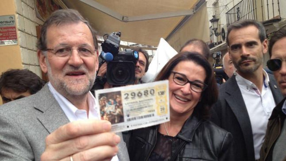 Mariano Rajoy recibe un décimo de lotería durante su recorrido por Estepona (Málaga).