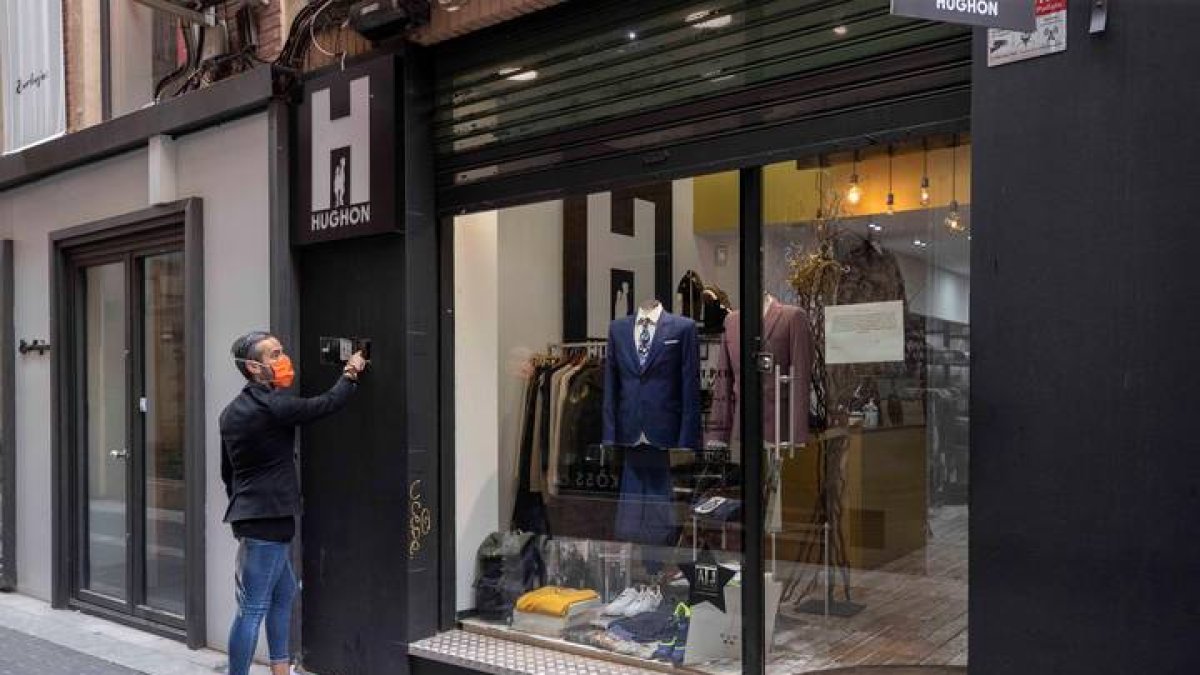 l propietario de una tienda de ropa de la calle jabonerias de Murcia, levanta la persiana de su comercio, hoy. MARCIAL GUILLÉN