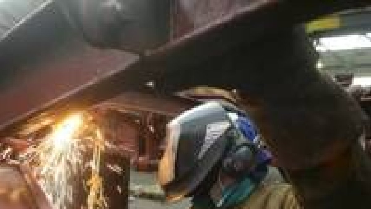 Un operario de Renfe pinta, en el taller de remolcado, uno de los vagones de la empresa ferroviaria