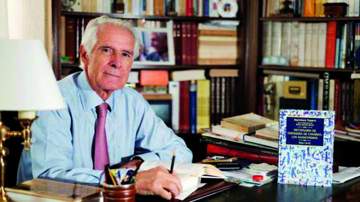 El catedrático de Filología Maximiano Trapero, en su biblioteca con un ejemplar del libro sobre topónimos guanches. DL