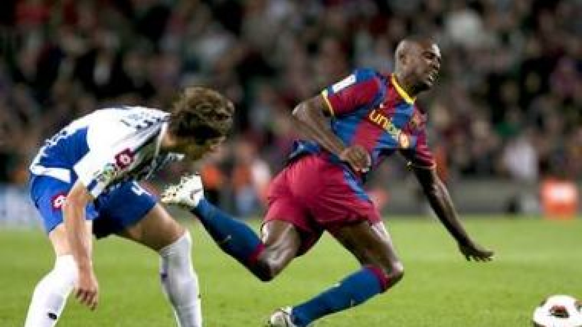 Eric Abidal, a la derecha, cae ante la entrada del mediocentro del Deportivo Rubén Pérez.