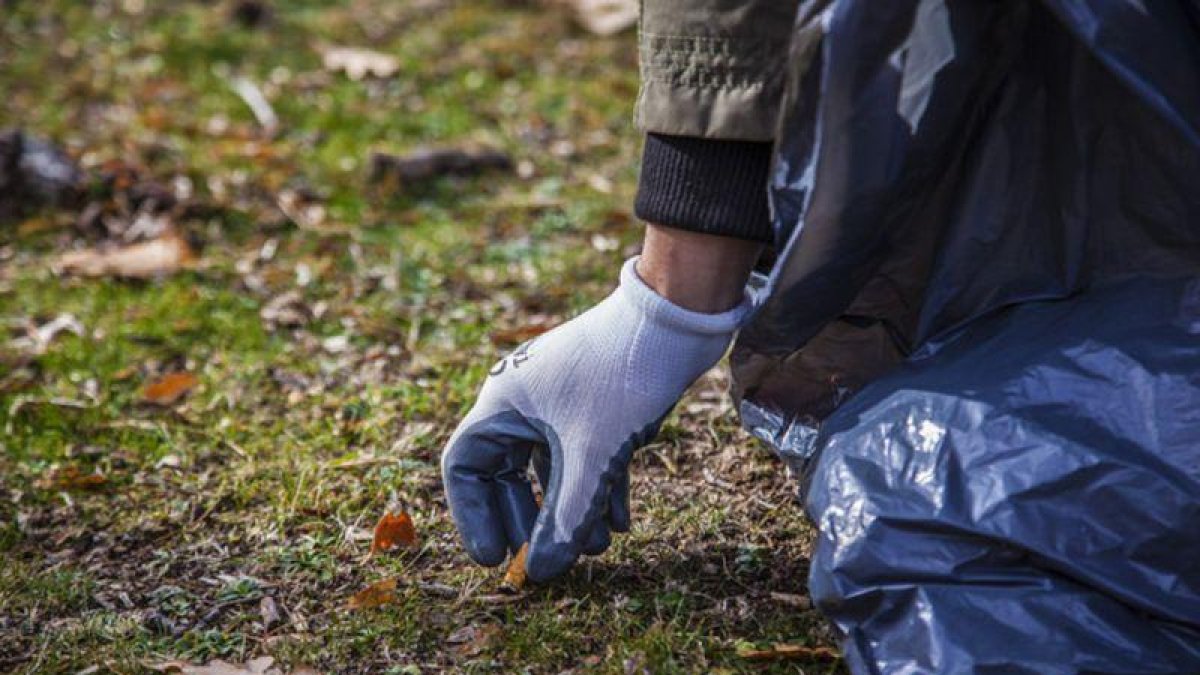 Proyecto Libera. Un voluntario recoge colillas en el campo.