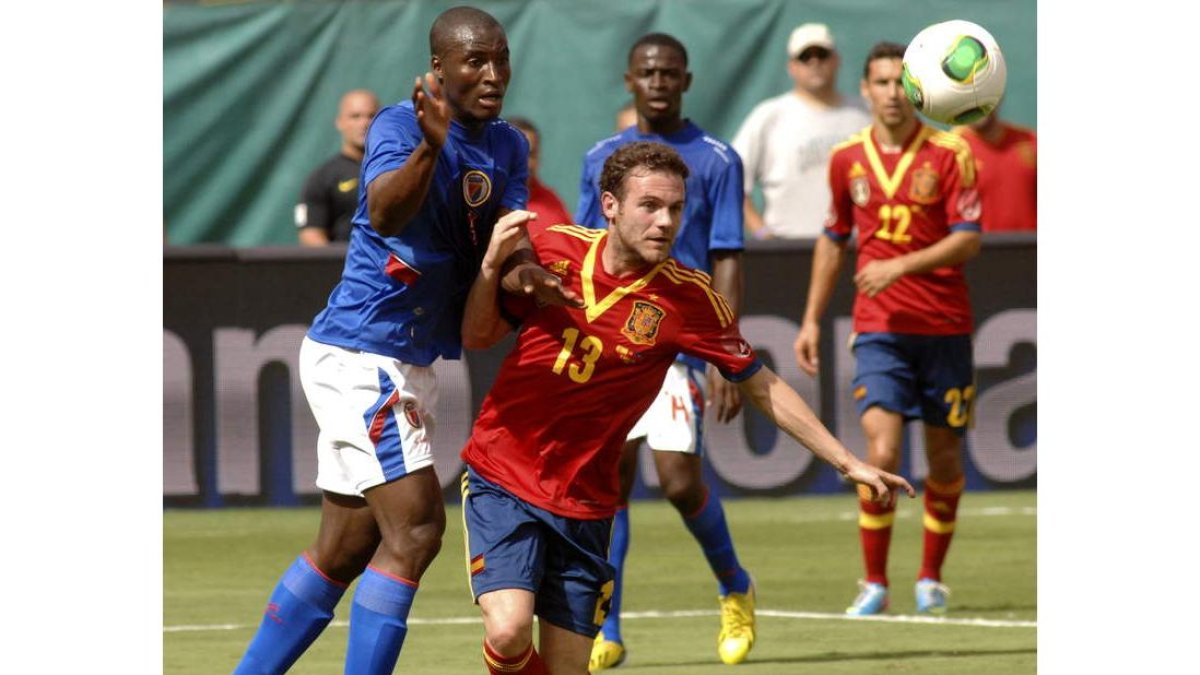 El delantero de la selección española, Juan Mata, lucha el balón con un jugador de Haití.