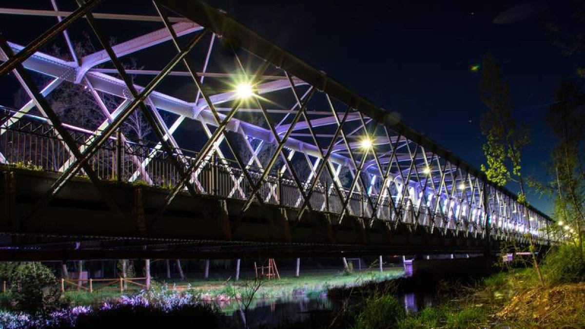 Sobre estas líneas, una imagen de la inauguración del puente, probablemente en junio del año 1895. A la derecha una foto actual de la infraestructura iluminada de noche.
