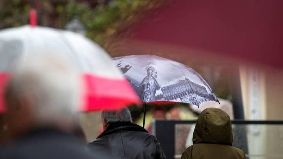 Varias personas se protegen del frío y la lluvia