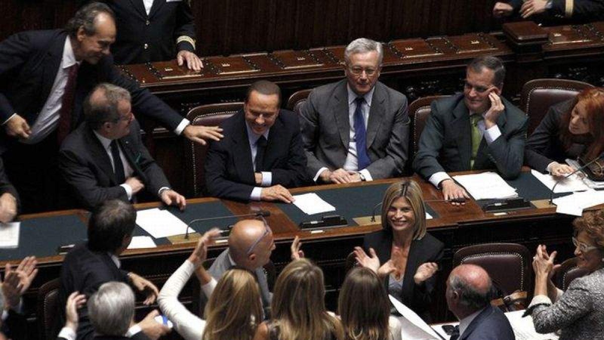 Berlusconi es felicitado por sus diputados tras la votación de la moción de confianza.