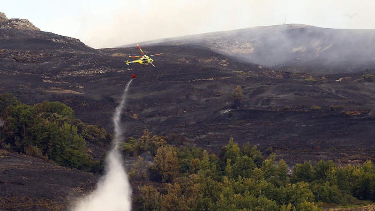 Un helicóptero trabaja en la extinción del incendio de Forna, que dejó un paisaje de desolación.