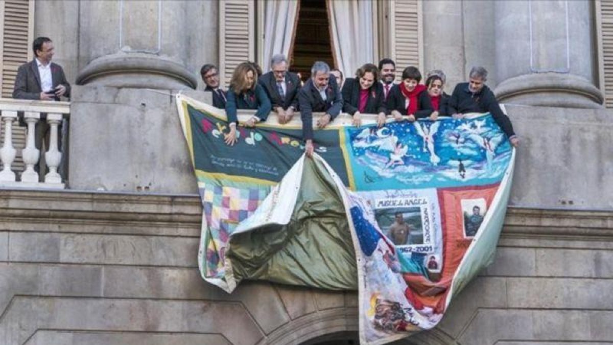 Colocación del tapiz en la fachada del Ayuntamiento de Barcelona, donde se recuerda a los fallecidos por el sida en el último año.