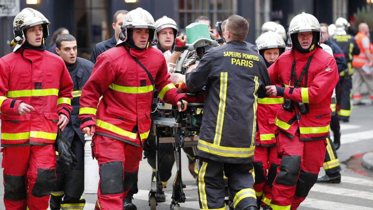 Bomberos y personal sanitario transportan a uno de los muchos heridos que provocó la explosión de la panadería parisina. IAN LANGSDON