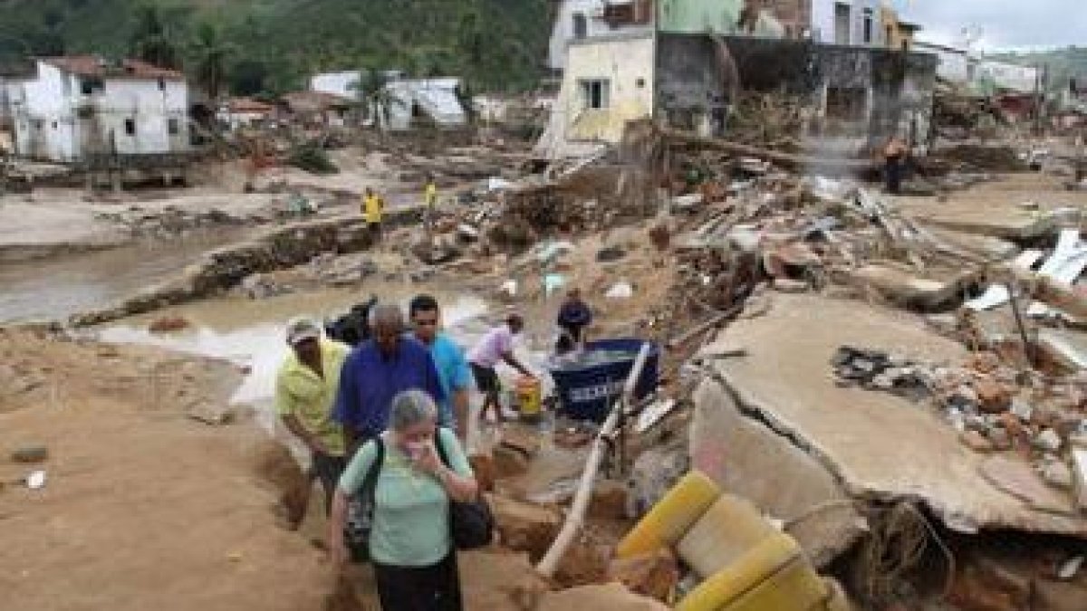 Vecinos de la ciudad de Santana do Mundau caminan entre los escombros.