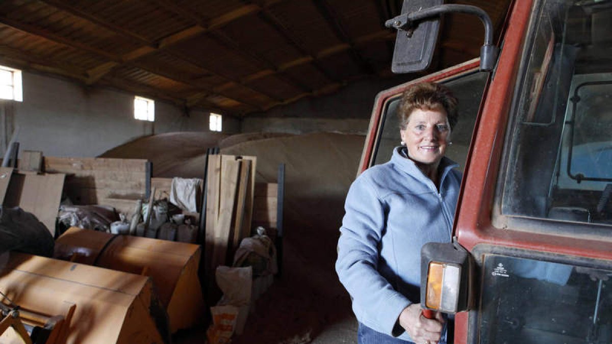 Una mujer agricultora, junto a su tractor.