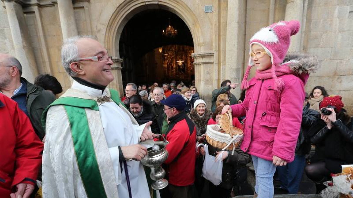 El párroco de Cacabelos, Jesús ÁLvarez, bendice el pan que lleva una niña