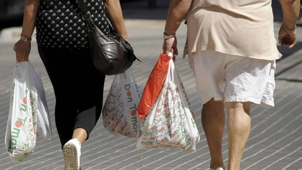 Dos mujeres llevan bolsas de plástico de la compra