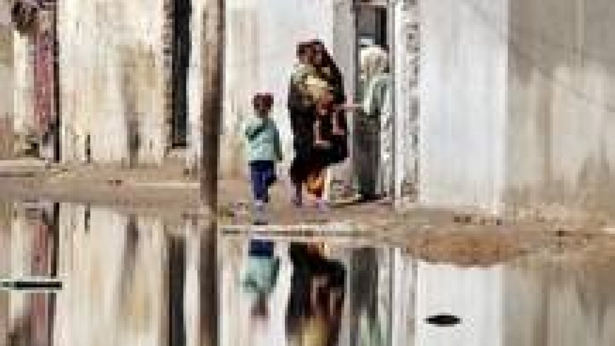 Una mujer lleva a sus hijos a casa en el barrio de Al Sáder, en Bagdad