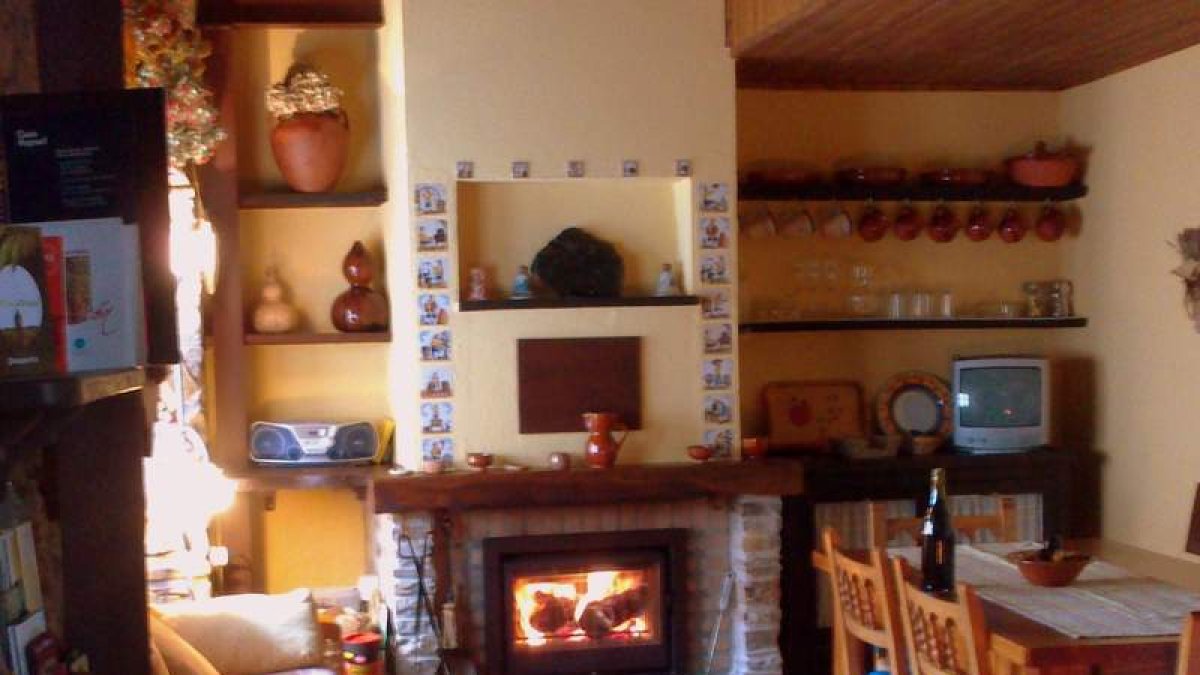 Salón con chimenea y fachada dela casa rural Los Cerezos, en el pueblo berciano de Rimor.