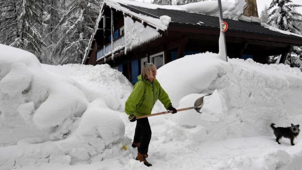 Una mujer aparta la nieve en Val DIsere, en los Alpes franceses.