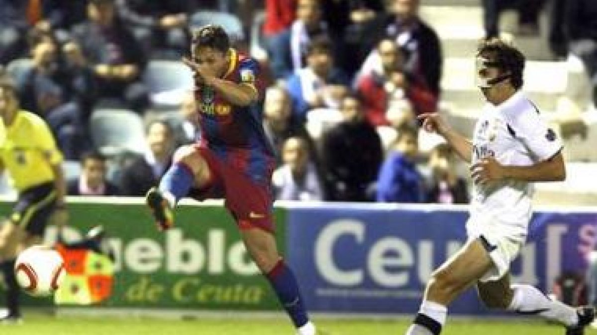 El barcelonista Adriano golpea el balón ante la oposición del defensor del Ceuta Baigorri.