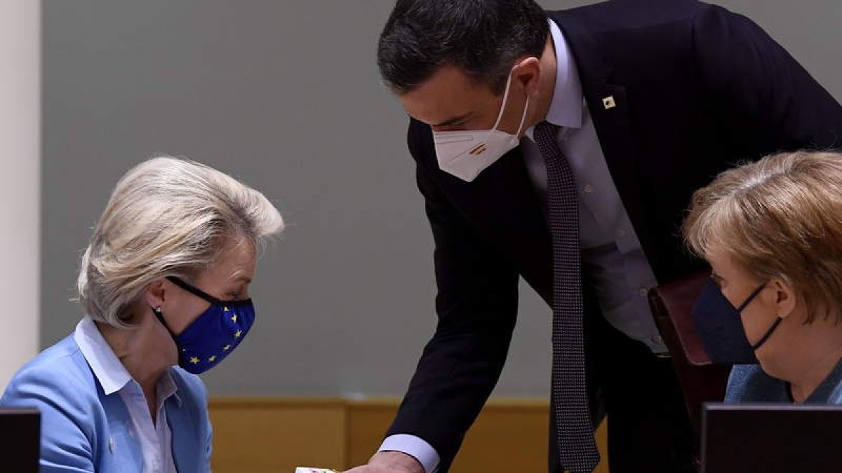 Sánchez le da un regalo a Ursula von der Leyen en presencia de Angela Merkel ayer, en Bruselas. JOHN THYS