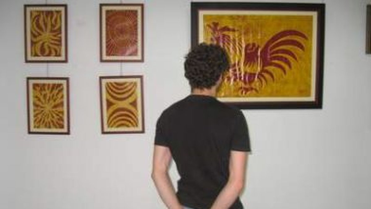 Un joven observa varias obras de Jaime Quintana.