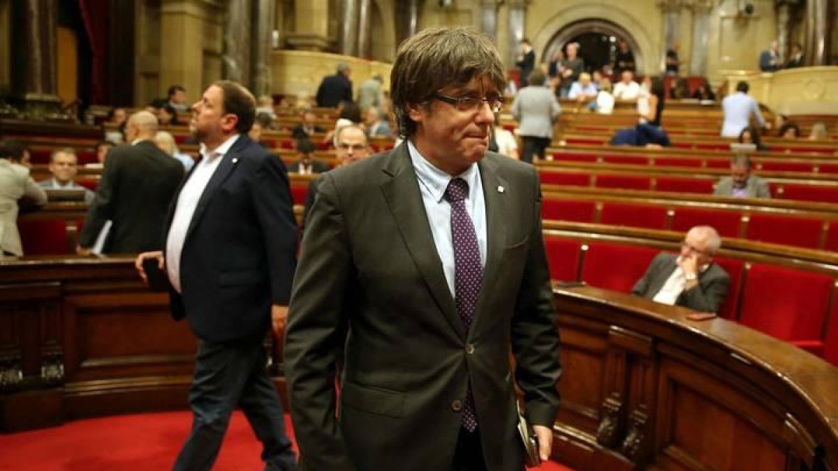 El presidente de la Generalitat, Carles Puigdemont (d) y el vicepresidente del Govern, Oriol Junqueras (i), abandonan el hemiciclo del Parlament de Cataluña.